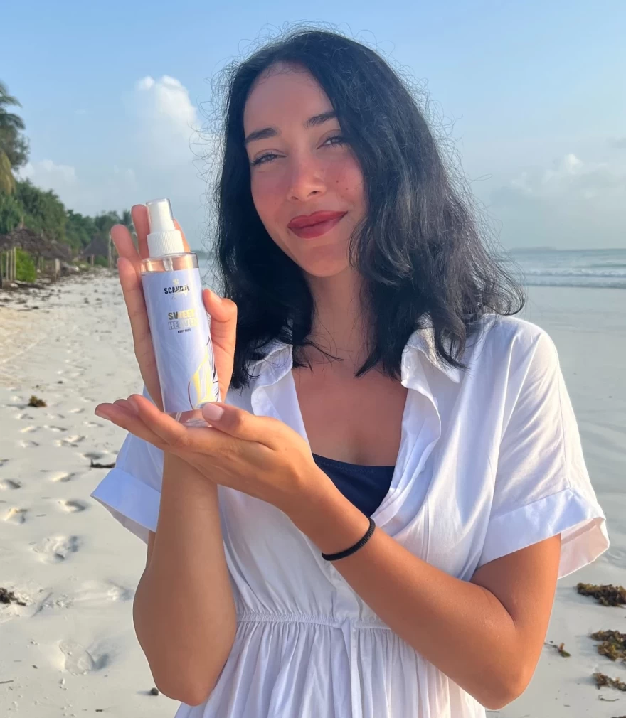 H Εύα Φούσκα κρατά ένα body mist Scandal Beauty