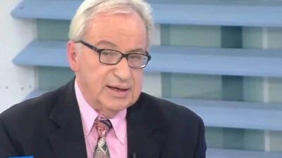 Ο Κώστας Λεφάκης με ροζ πουκάμισο, γραβάτα και σκούρο γκρι σακάκι