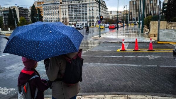 Μπαμπάς και γιος με ομπρέλα σε βροχερό τοπίο της Αθήνας