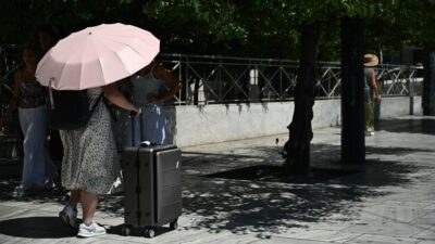 Μια γυναίκα με βαλίτσες και ομπρέλα